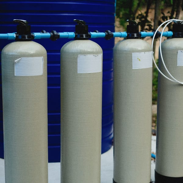Row of resin treatment tanks with control valves and blue piping